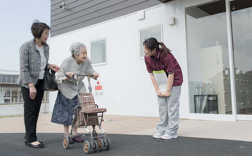 職員が入居者の歩行を支援している屋外での日常風景。